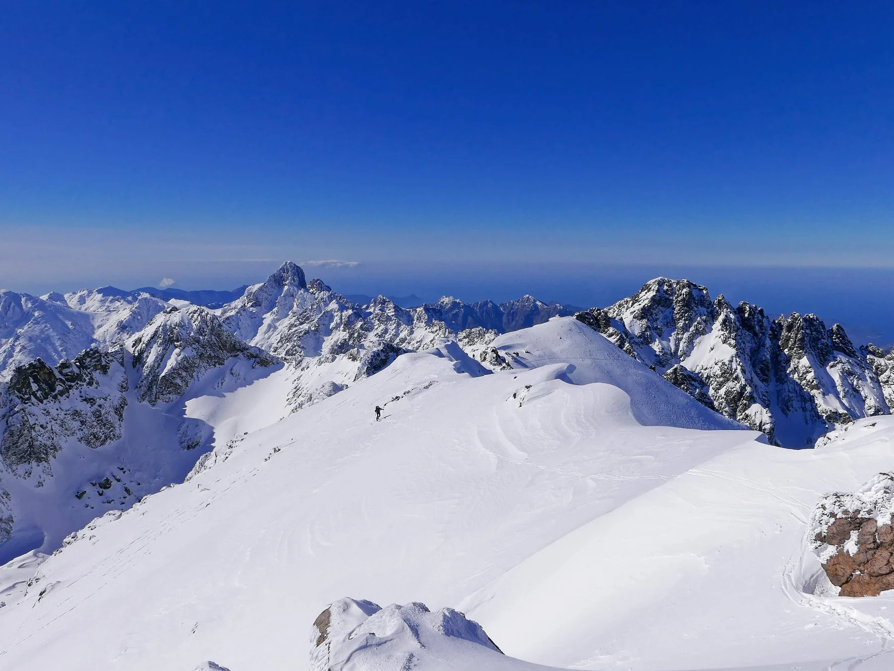Skieur sur une crête enneigée pendant l’ascension du Monte Cinto à ski de randonnée, lors de l’Alpine Line en Corse.
